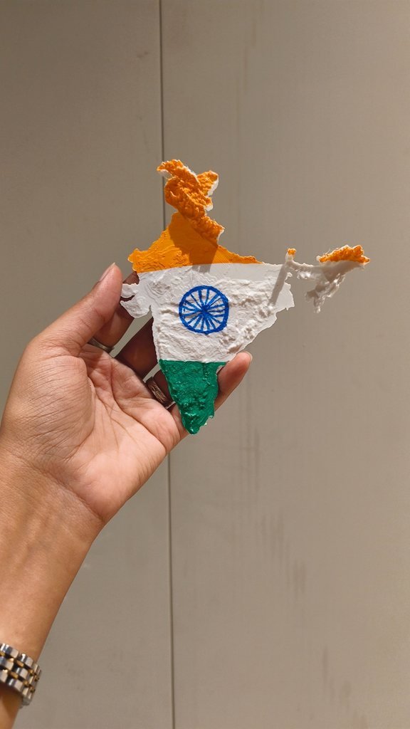 A 3D printed relief map of India painted saffron, white and green, held in a hand