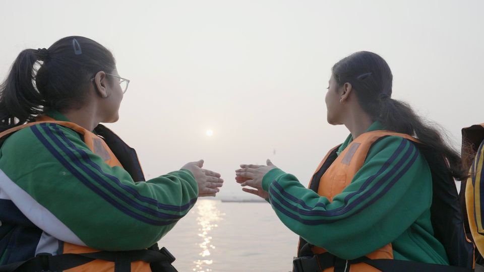 Two students greet the sunrise from a boat on the Ganga during a school trip, Varanasi